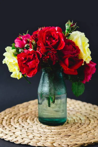 Lenyűgöző összetétele színes rózsák egy üvegvázában a fonott szalvéta — Stock Fotó