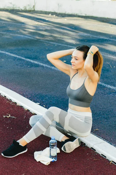 Giovane donna seduta a terra con una bottiglia d'acqua dopo aver fatto jogging all'aperto — Foto Stock