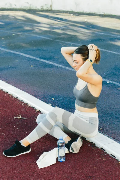 Молода жінка сидить на землі з пляшкою води після бігу на відкритому повітрі — стокове фото