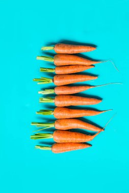 birkaç taze havuç mavi bir arka plan üzerinde üst üste yalan.