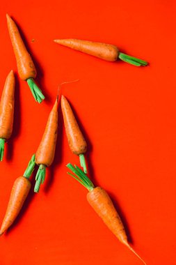 Kırmızı arka planda birkaç taze havuç.