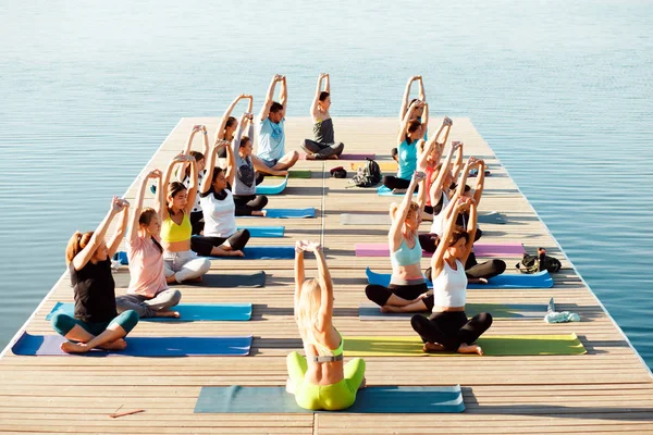 Gölün yakınındaki bir pontonda yoga derslerine katılan büyük bir grup insan..