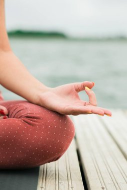 Asya genç güzel kız göl kenarında iskelede açık havada meditasyon.