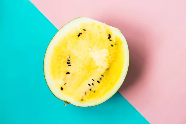 half of ripe yellow watermelon on pink-blue background