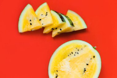 birkaç üçgen adet ve kırmızı bir arka plan üzerinde olgun sarı karpuz yarısı