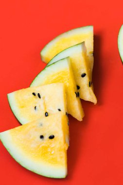 birkaç üçgen adet ve kırmızı bir arka plan üzerinde olgun sarı karpuz yarısı