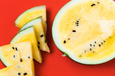 birkaç üçgen adet ve kırmızı bir arka plan üzerinde olgun sarı karpuz yarısı