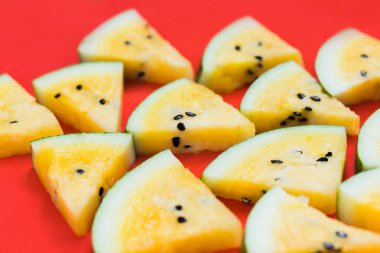 kırmızı arka plan üzerinde olgun sarı karpuz üçgen parçaları bir sürü