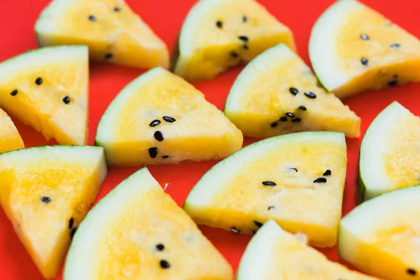 kırmızı arka plan üzerinde olgun sarı karpuz üçgen parçaları bir sürü