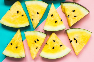 mavi-pembe arka plan üzerinde olgun sarı karpuz üçgen dilimleri kesti