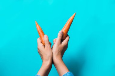 birkaç taze havuç mavi bir arka plan üzerinde üst üste yalan.