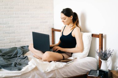 Laptop kullanan genç bir kadın, virüs karantinadayken internet üzerinden müşterisiyle iletişim kuruyor. Rahat ofis yeri, uzaktan çalışma, e-öğrenme konsepti.