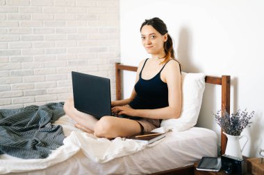 Laptop kullanan genç bir kadın, virüs karantinadayken internet üzerinden müşterisiyle iletişim kuruyor. Rahat ofis yeri, uzaktan çalışma, e-öğrenme konsepti.