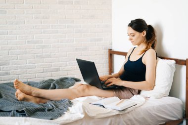 Laptop kullanan genç bir kadın, virüs karantinadayken internet üzerinden müşterisiyle iletişim kuruyor. Rahat ofis yeri, uzaktan çalışma, e-öğrenme konsepti.