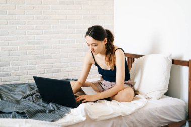 Laptop kullanan genç bir kadın, virüs karantinadayken internet üzerinden müşterisiyle iletişim kuruyor. Rahat ofis yeri, uzaktan çalışma, e-öğrenme konsepti.