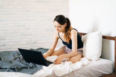 Laptop kullanan genç bir kadın, virüs karantinadayken internet üzerinden müşterisiyle iletişim kuruyor. Rahat ofis yeri, uzaktan çalışma, e-öğrenme konsepti.