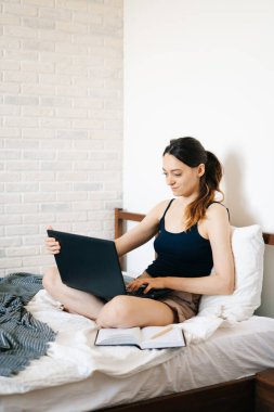 Laptop kullanan genç bir kadın, virüs karantinadayken internet üzerinden müşterisiyle iletişim kuruyor. Rahat ofis yeri, uzaktan çalışma, e-öğrenme konsepti.