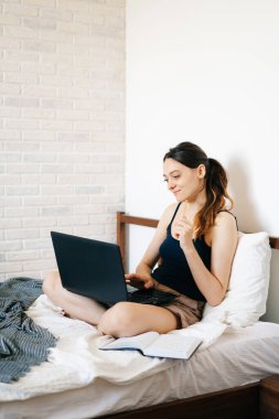 Laptop kullanan genç bir kadın, virüs karantinadayken internet üzerinden müşterisiyle iletişim kuruyor. Rahat ofis yeri, uzaktan çalışma, e-öğrenme konsepti.