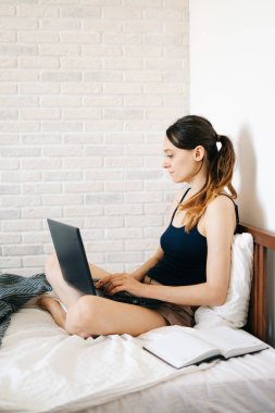 Laptop kullanan genç bir kadın, virüs karantinadayken internet üzerinden müşterisiyle iletişim kuruyor. Rahat ofis yeri, uzaktan çalışma, e-öğrenme konsepti.