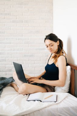 Laptop kullanan genç bir kadın, virüs karantinadayken internet üzerinden müşterisiyle iletişim kuruyor. Rahat ofis yeri, uzaktan çalışma, e-öğrenme konsepti.