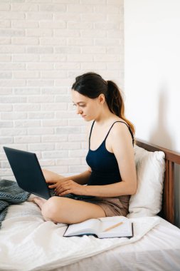 Laptop kullanan genç bir kadın, virüs karantinadayken internet üzerinden müşterisiyle iletişim kuruyor. Rahat ofis yeri, uzaktan çalışma, e-öğrenme konsepti.