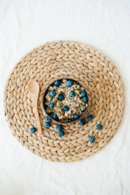 Taze yabanmersinli yulaf lapası. Kahverengi doğal deniz yosunu peçetesine ve doğal ahşap bambu kaşığına karşı sağlıklı vejetaryen kahvaltısı gevrekleri. Temiz yiyecek kavramı.