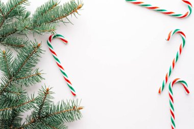 Noel ya da yeni yıl arkaplanı, Noel şekerleri ve köknar dallarının sade kompozisyonu, düzlük, düzlük, karşılama metinleri için boş alan.