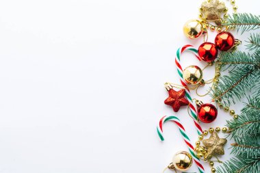 Noel aralığı. Noel balonları, çelenkler, kırmızı ve altın madalyalar, Noel şekerleri ve beyaz arka planda köknar dalları. Düz konum, üst görünüm, kopyalama alanı.