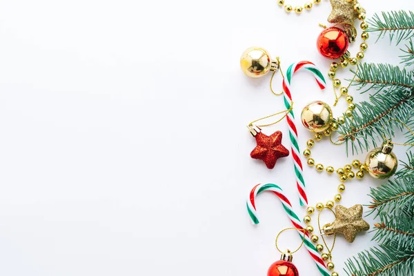 Christmas frame. Christmas balloons, garlands, red and gold decorations, Christmas candies and fir branches on a white background. Flat lay, top view, copy space.