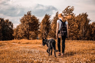 Sonbaharda parkta veya ormanda siyah Alman çoban köpeği ile Kız