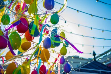 sripes ve çatılar arka plan ile mavi gökyüzünde ağaç üzerinde multiclored balonlar ve kurdeleler. Çok renkli, kutlamanın bir parçası. Parlak güneşe ve yaz gökyüzüne karşı