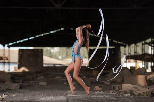 Genç kız dışarıda ritmik jimnastik yapıyor.