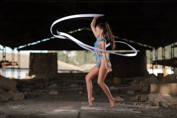 Genç kız dışarıda ritmik jimnastik yapıyor.