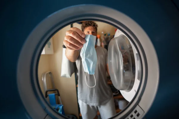 man putting a mask in a washing machine