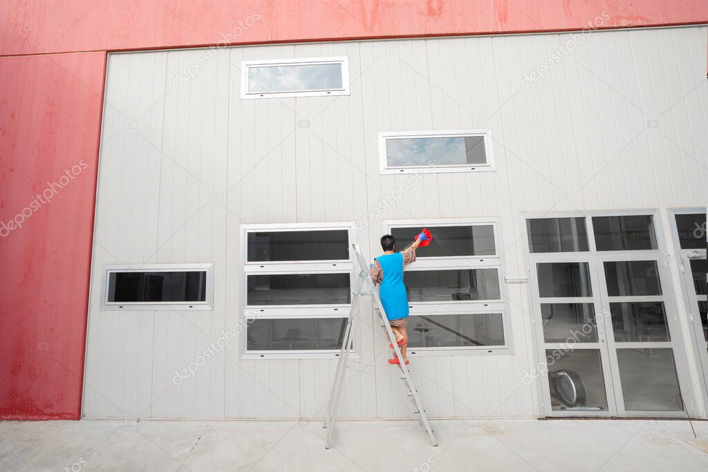 woman climbing on a ladder cleaning windows