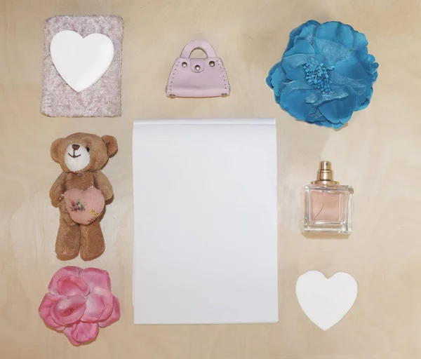 Layout of cute items, bear, bag, perfume and women\'s accessories, flower, notebook on the table