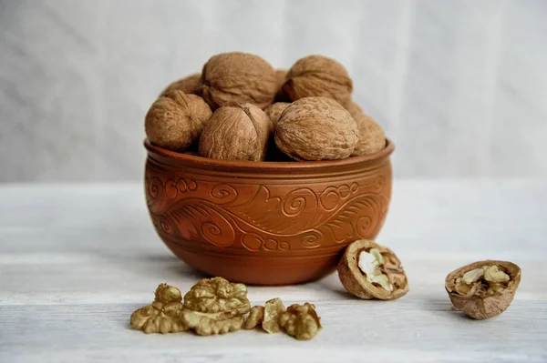 Walnoten, noten in aardewerk op een witte tafel. Zijaanzicht — Stockfoto