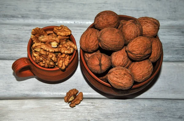 Walnoten, noten in aardewerk, gepeld en ongepeld op een witte tafel. van bovenaf bekijken — Stockfoto