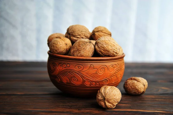 Walnoten, noten in aardewerk op een houten tafel. Zijaanzicht — Stockfoto