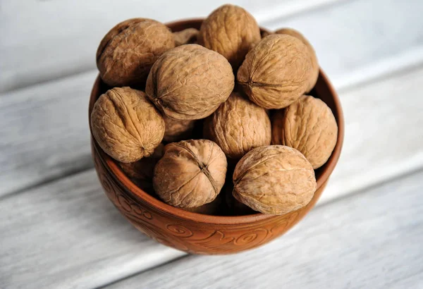 Walnoten, noten in aardewerk op een witte tafel. van bovenaf bekijken — Stockfoto