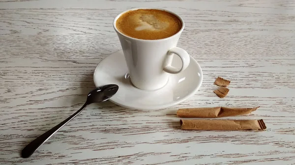 Kaffe med mjölk i en vit mugg på ett vitt bord med sockerpåsar — Stockfoto