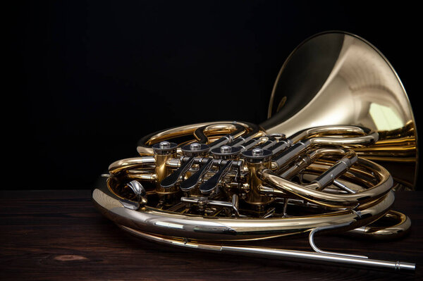 Musical instrument, French horn on a wooden surface on a black background