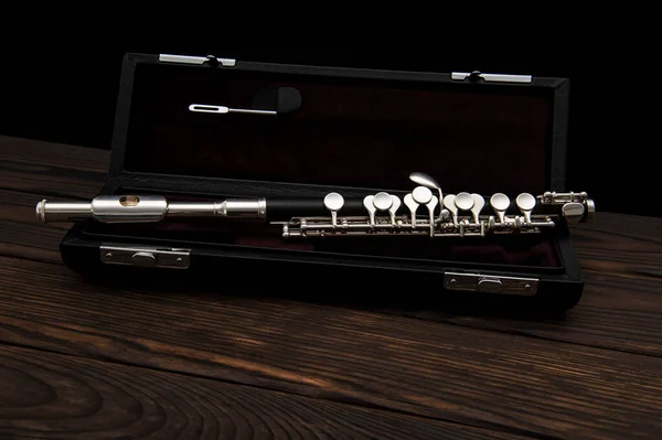 Musical instrument, flute with a case on a wooden surface on a black background