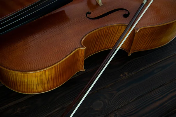 大提琴躺在木制的表面上 上有一个弓 案文的位置 — 图库照片