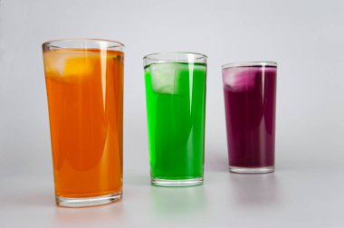 Beyaz arka planda buzlu üç bardak farklı meyve suyu.