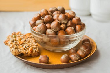 Kahverengi plaka üzerinde bir cam kase ve somun kurabiye fındık yığını