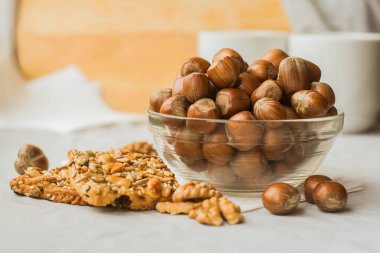 Beyaz peçete üzerinde bir cam kase, somun kurabiye ve ceviz fındık yığını