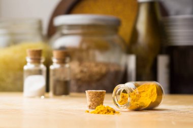 Bir mutfak masasında Curcuma küçük yığını, bir masada yakın tuz ve biber ile kavanoz, Curcuma ile cam düşmüş kavanoz