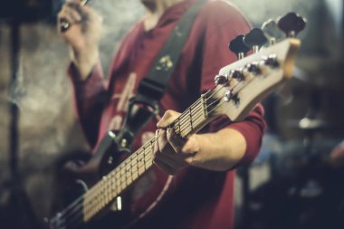 Buhar bulutları ile çevrili bir stüdyoda bas gitar çalan bir adam