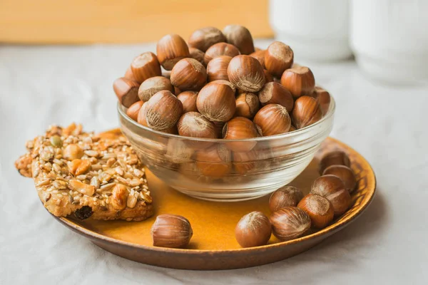 Kahverengi plaka üzerinde bir cam kase ve somun kurabiye fındık yığını